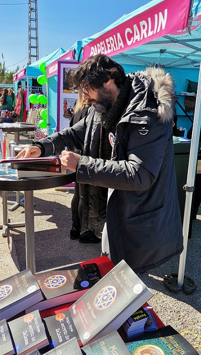 Sergio Reyes firmando libros en la Feria del comercio de Alcantarilla (lector recortado por protección de datos)