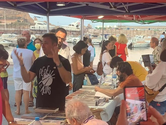 Foto de los eventos del verano 2022: Sergio Reyes firmando en la Feria del libro de Águilas mientras Fran se explaya explicando sus novelas ;)