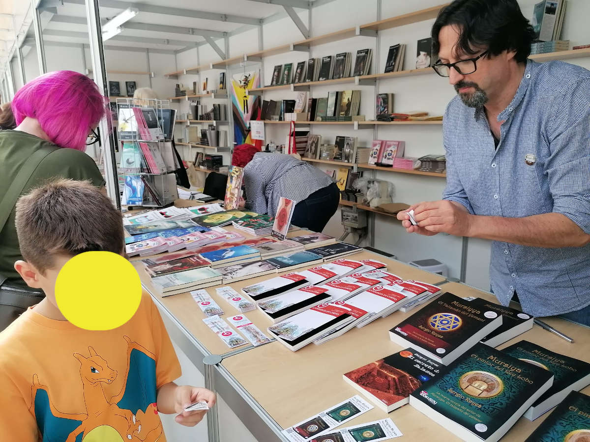Sergio Reyes repartiendo pegatinas en la caseta de Ediciones Dokusou de la Feria del libro de Murcia 2022