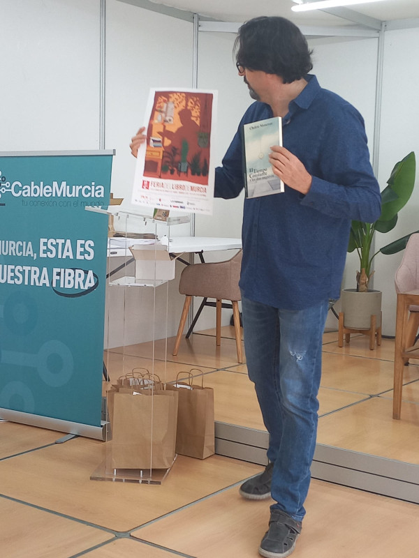 Sergio Reyes muestra parte de los obsequios que componen la bolsa de obsequio a los participantes en el Encuentro-taller con el programa de acompañamiento a personas mayores de Solidarios para el desarrollo celebrado en la Feria del libro de 2022 en forma de taller de microrrelatos