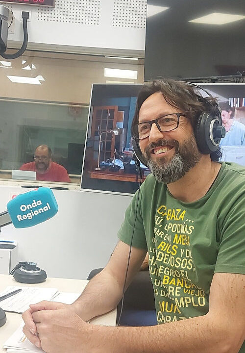 Sergio Reyes sonriente en los estudios de Onda Regional de Murcia durante la emisión del programa El último Peldaño (al fondo, en la pecera de controles, Paco Valera)