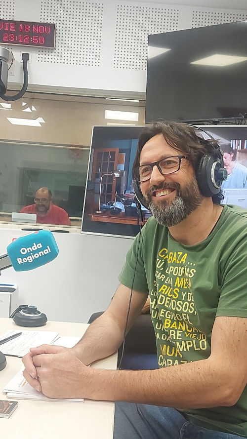 Sergio Reyes sonriente en los estudios de Onda Regional de Murcia durante la emisión del programa El último Peldaño (al fondo, en la pecera de controles, Paco Valera)