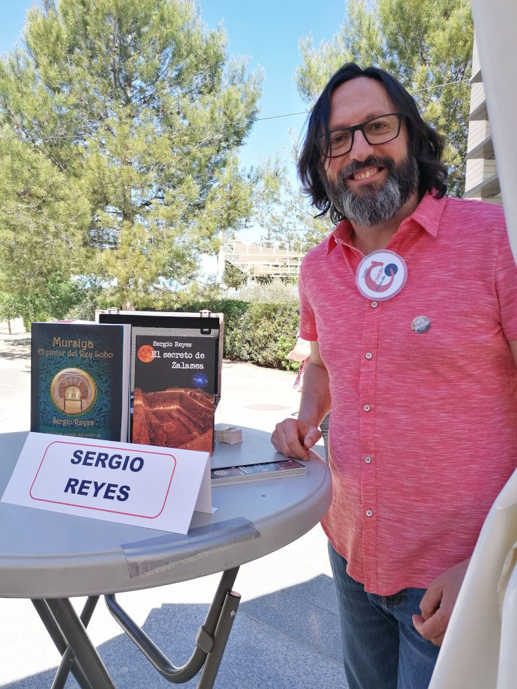 Sergio Reyes posa junto a su mesa de firmas en la feria del libro de Alcantarilla 2023